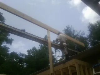 Carpenter setting a ridge beam over a new addition frame — Ice Dam Removal by Roofing Brothers in Carteret