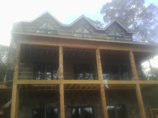 Dormers and porch framing on a large log home under construction — Roof Coating work by our crew in Carteret