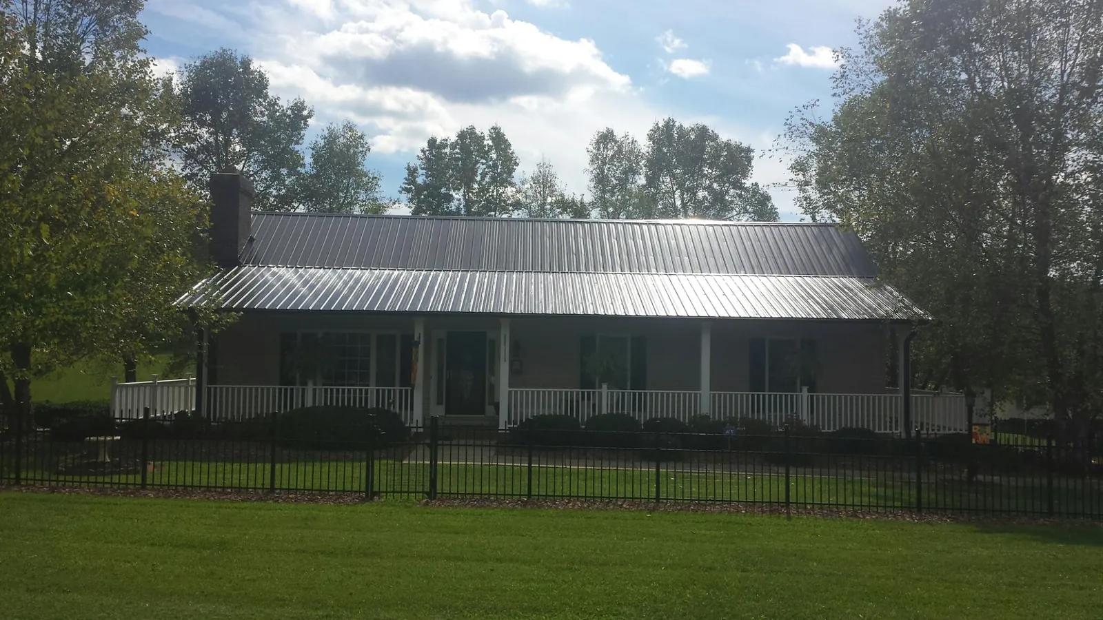 Gray metal roof on a brick ranch with a full width front porch in Carteret
