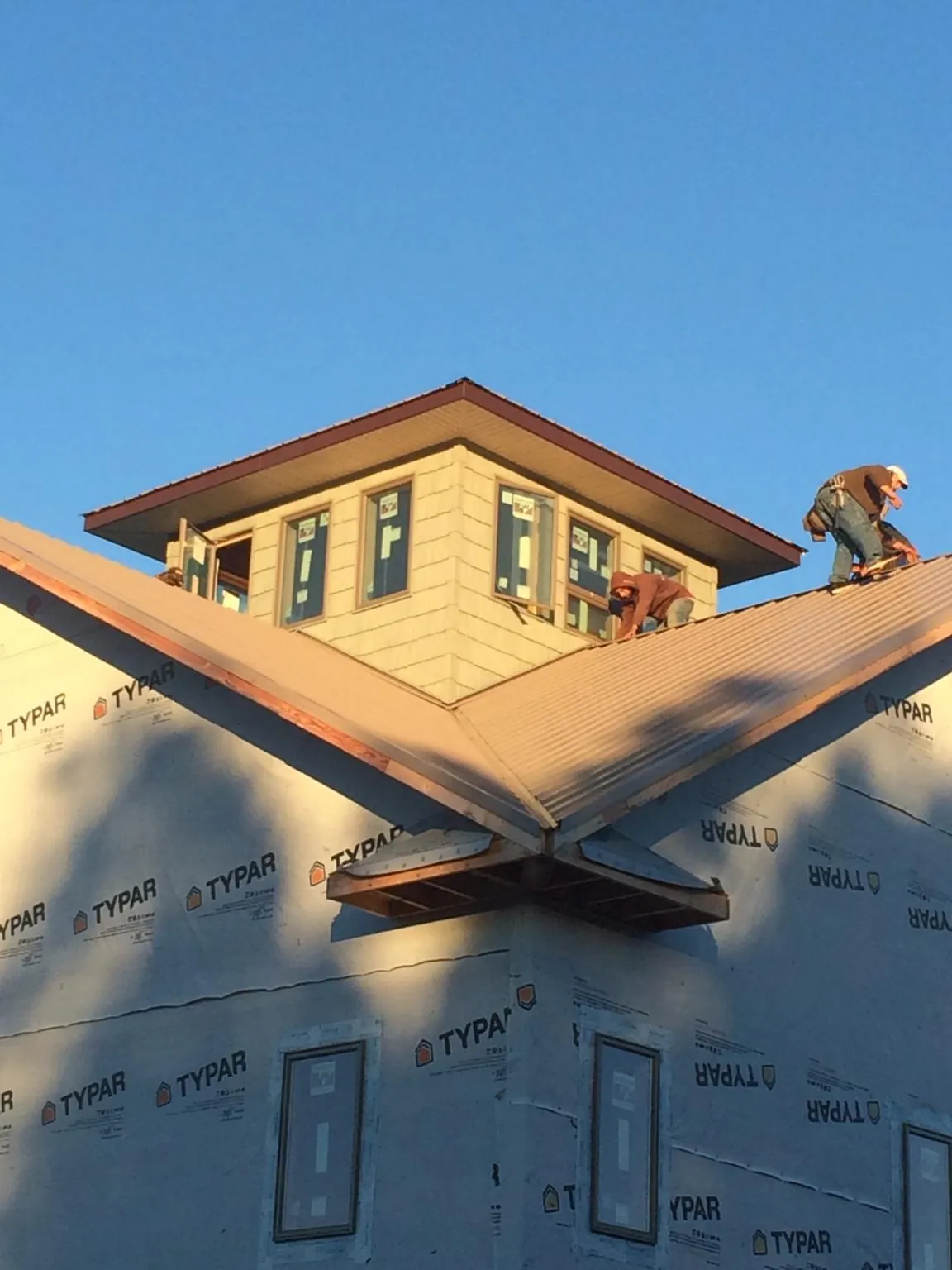 Roofers working around a rooftop cupola on a new metal roof at sunset — Roof Waterproofing in Carteret by Roofing Brothers